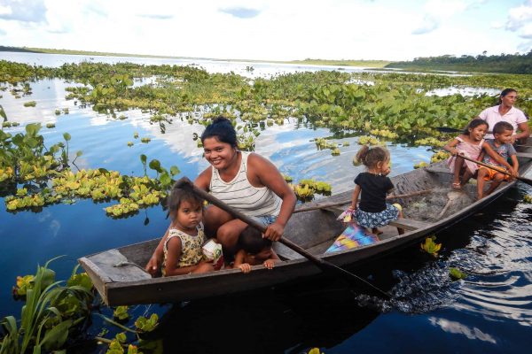 A resident family of the Brazilian Rosewood project paddling in a canoe in shallow waters and wetlands.