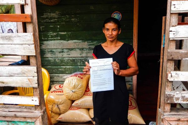 Une résidente du projet de bois de rose brésilien tenant un certificat de propriété foncière.