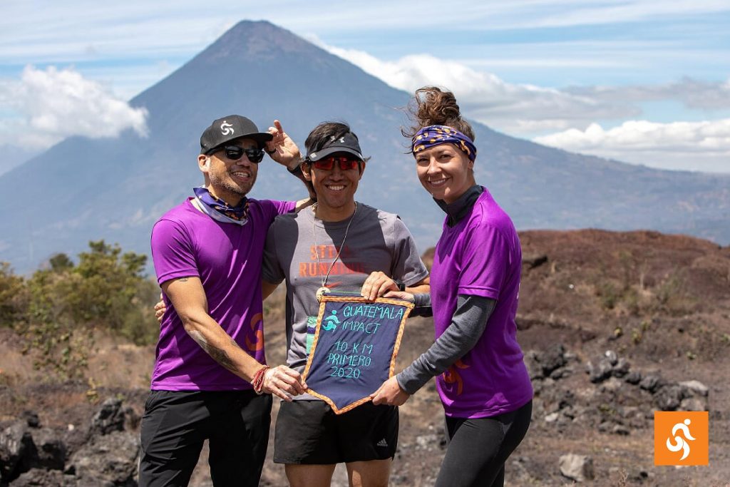 Tres corredores del Maratón de Impacto frente a un volcán en Guatemala