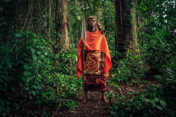 El jefe Wilondo Baswa, jefe consuetudinario de la tribu Ntombezale, clan Lobalu, de Mai Ndombe, RDC. El jefe consuetudinario es el representante de los ancestros en su comunidad. Estas prendas reflejan el poder ancestral y suelen llevarse durante las grandes ceremonias tradicionales. Las plumas de águila y la piel de leopardo representan la fuerza ancestral, mientras que el color rojo representa el poder. Además, la lanza ancestral o el machete representan a un guerrero. Fotografía: Filip C. Agoo para Wildlife Works Carbon.