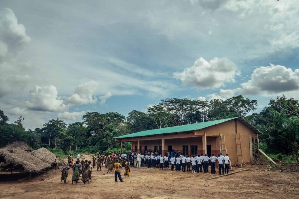 Niños y visitantes reunidos frente a una escuela en el proyecto Mai Ndombe, RDC. Fotografía: Filip C. Agoo para Wildlife Works Carbon.