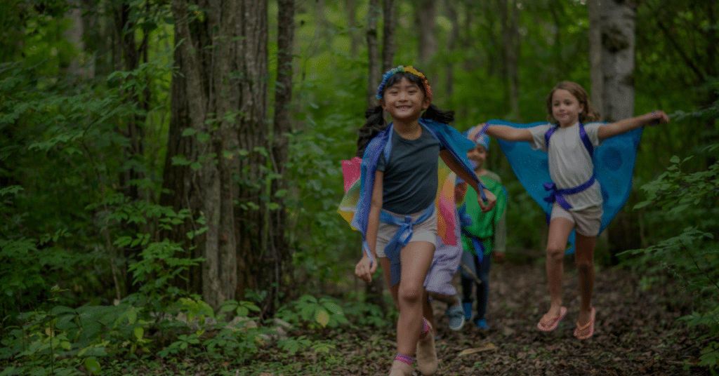 Three kids taking part in earth day activities by walking on a path in a forest with vibrant outfits
